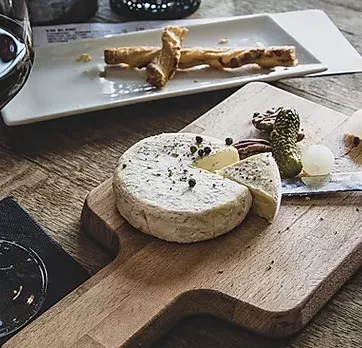 Fromage sur une planche à découper. un quart du fromage est coupé.